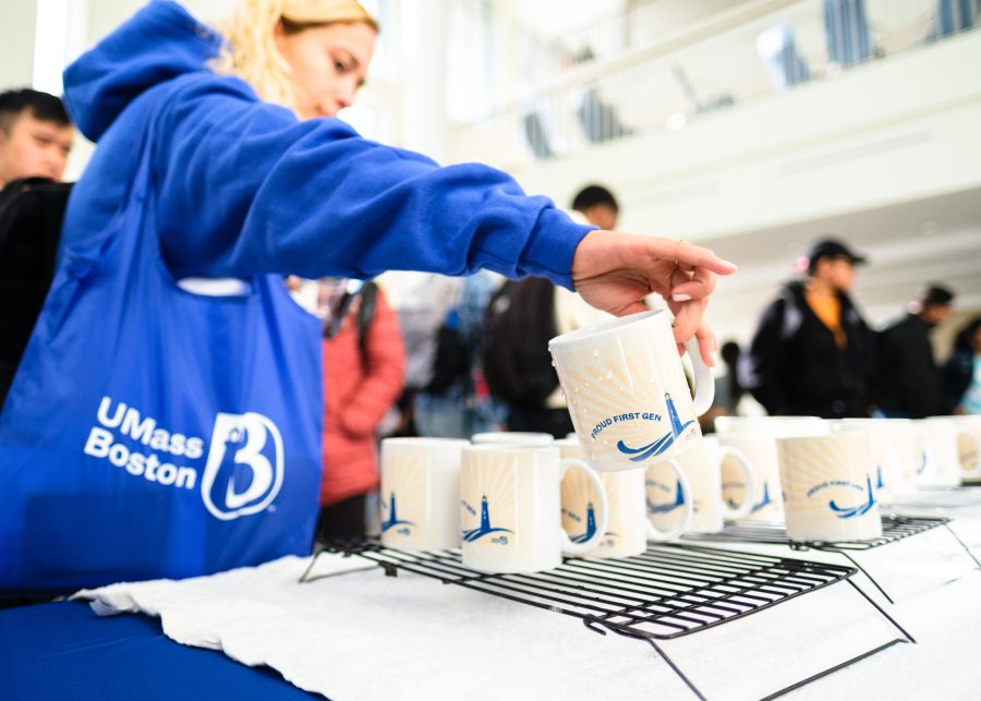 A student reaching for a custom mug given out during First Gen Week in Campus Center.
