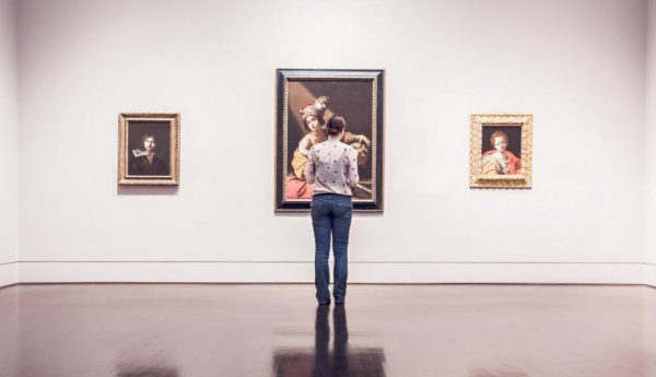 A woman views artwork in a gallery. Photo sourced from Unsplash.