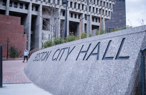 A person walks by Boston City Hall. Photo by Colin Tsuboi / Mass Media Staff.