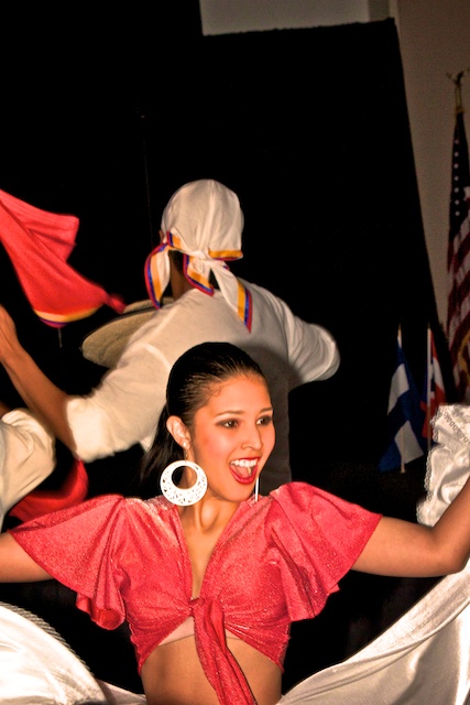 A member of the dance group "Bajucol" smiles to the crowd as she performs a Columbian dance.