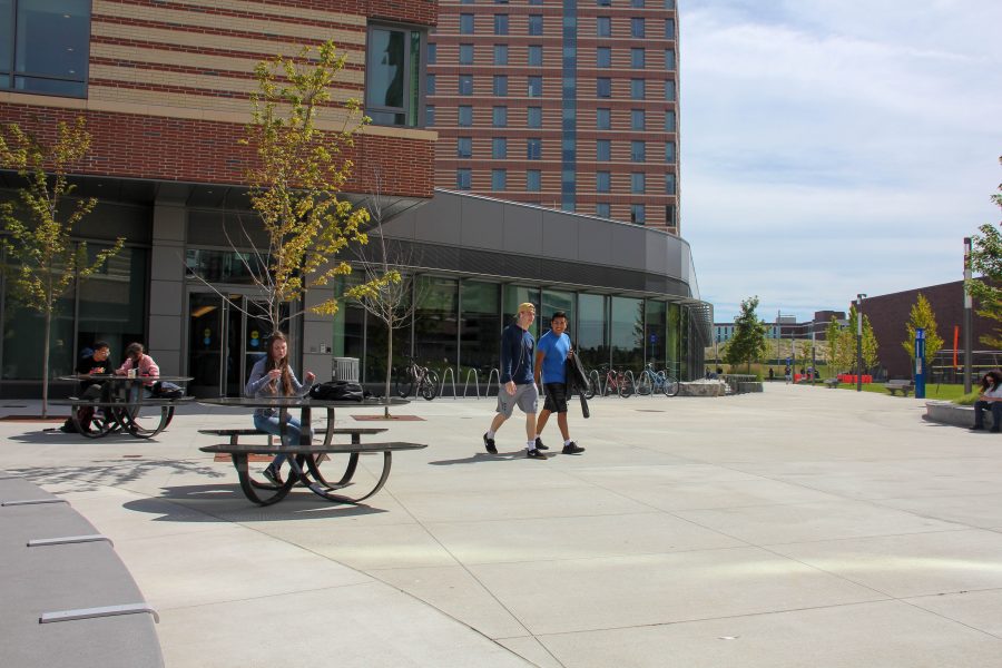 Two students exit the East Residence Hall on Thursday, September 5th. Along the sidewalk and by the doors, various other students sit outside enjoying the 70 degree weather while it lasts.