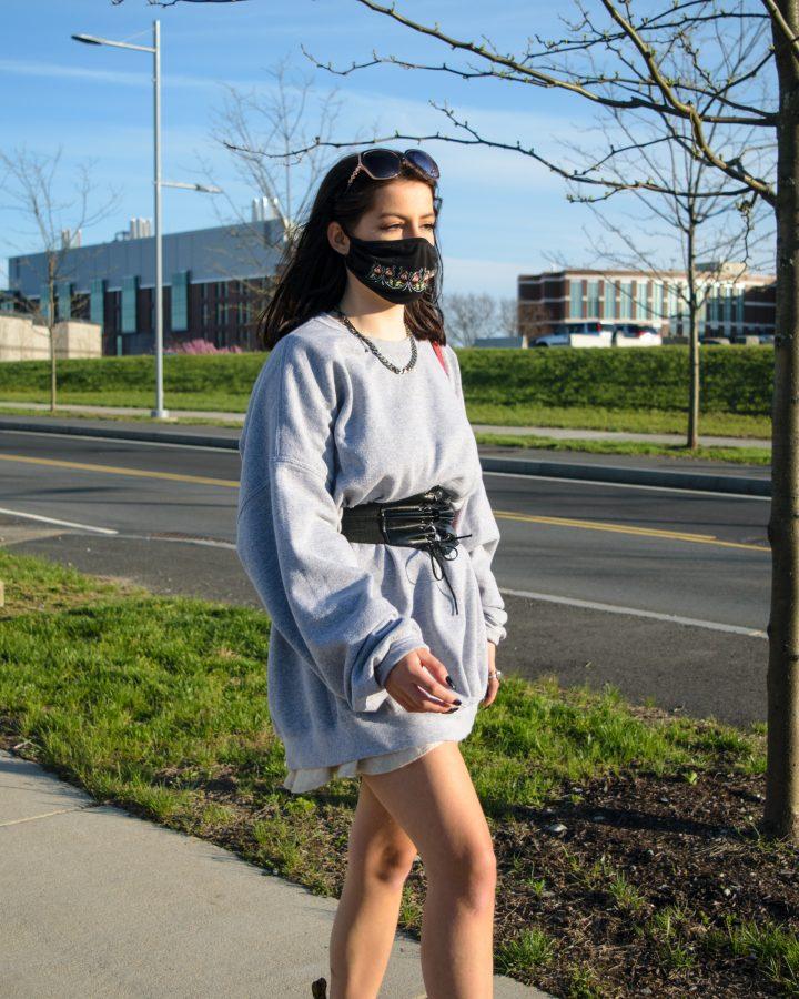 A girl takes a walk at the UMass Boston campus with her mask on.