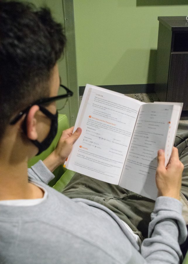 Francis, a freshman, reads his Japanese language textbook in the East Hall of the campus dorms.