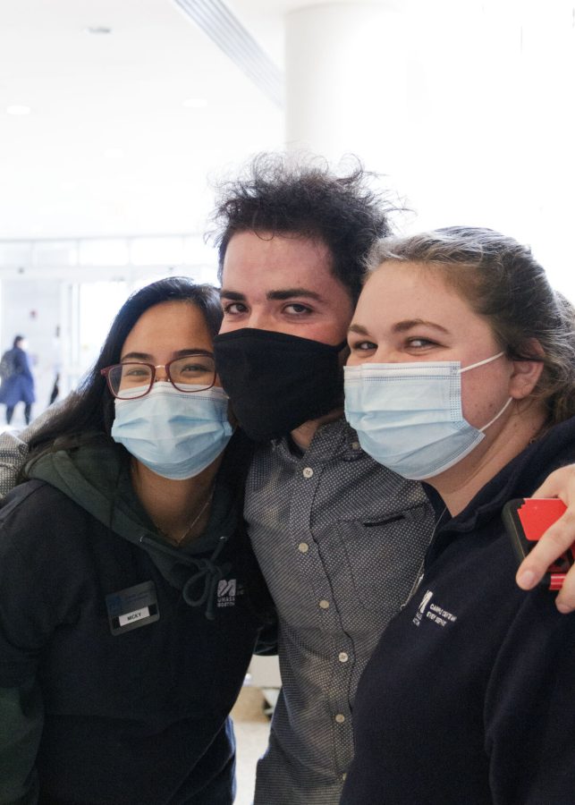 Students working at the Campus Center Information Desk pose for a photo wearing masks.