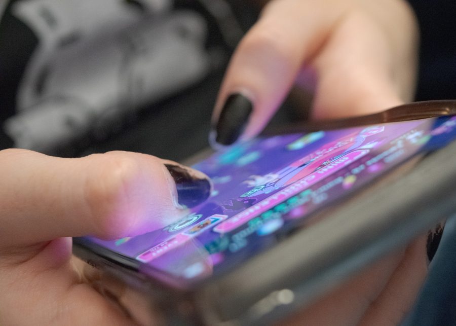 A UMass Boston Student passes time by playing games on her phone in a common room.