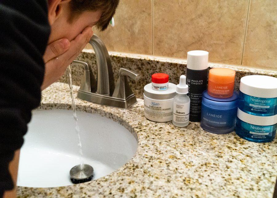 A teen washes their face with skincare products.