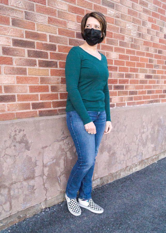 An outfit of dark washed jeans, green shirt and canvas shoes.