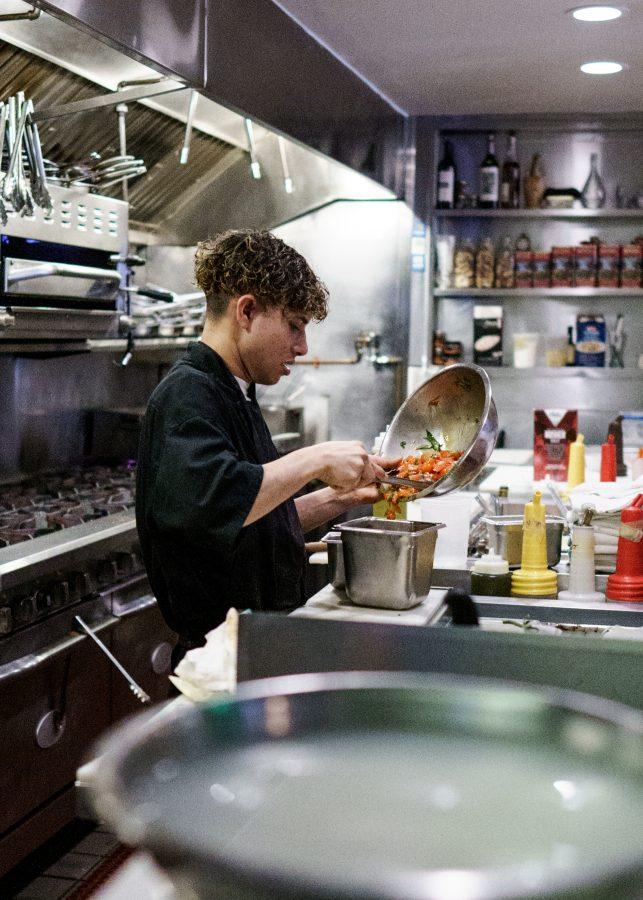 Employee David works behind the food counter at Monica’s Trattoria preparing vegetables on March 25, 2022.