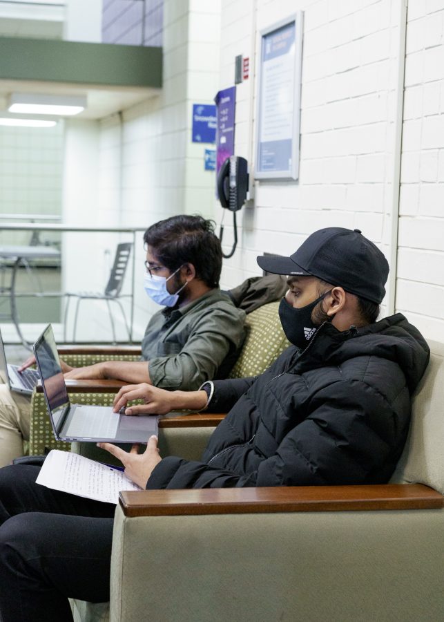 UMass Boston students Madhu Makireddy and Sandeep Singh (L-R) study while wearing masks in Wheatley Hall on Thursday, March 30, 2022.