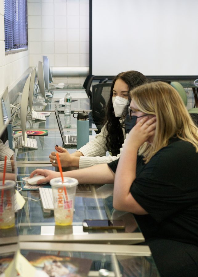 UMass Boston students Meaghan Shea (Front) and Hannah Ortiz (Back) wear masks while working on assignments in the Wheatley Digital Studio.