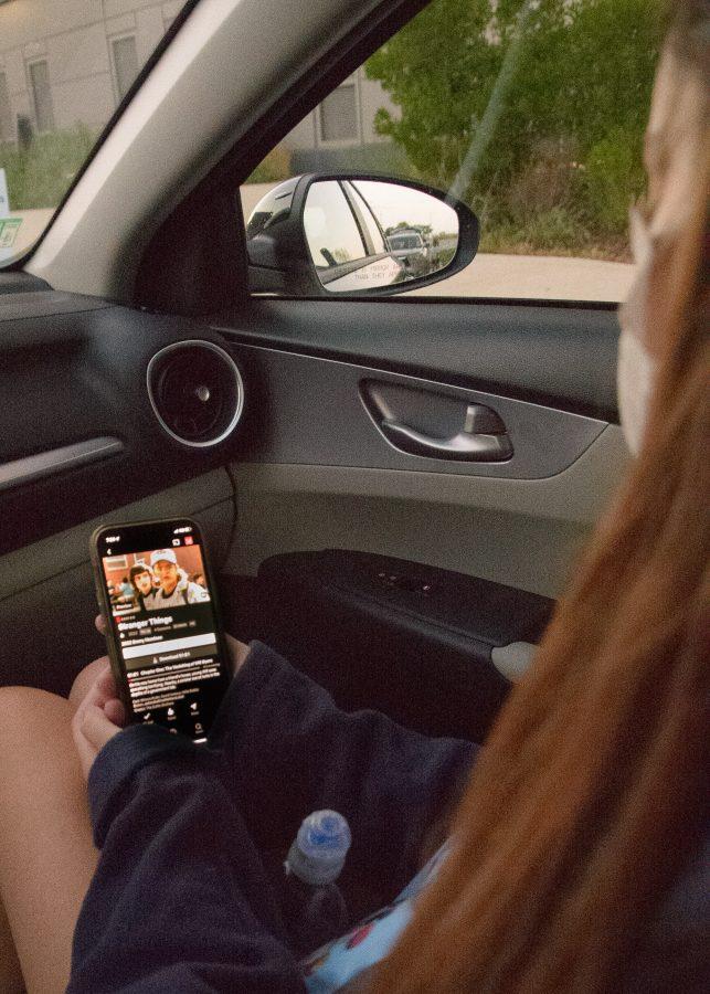 A student catches up on the newest season of Stranger Things in her friends car after a stressful day.