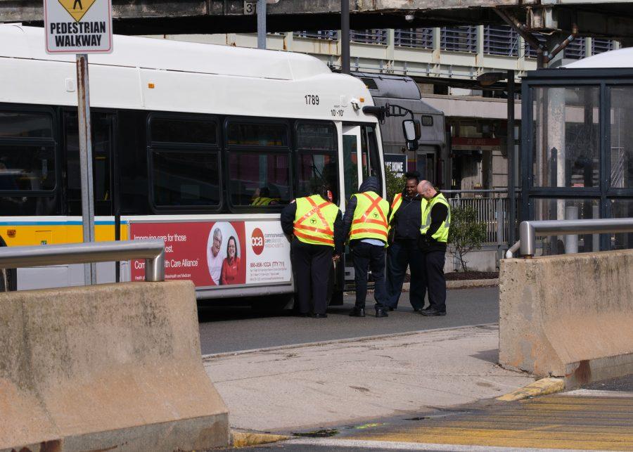 MBTA employees take a break outside of a bus sitting at the JFK/UMass station.