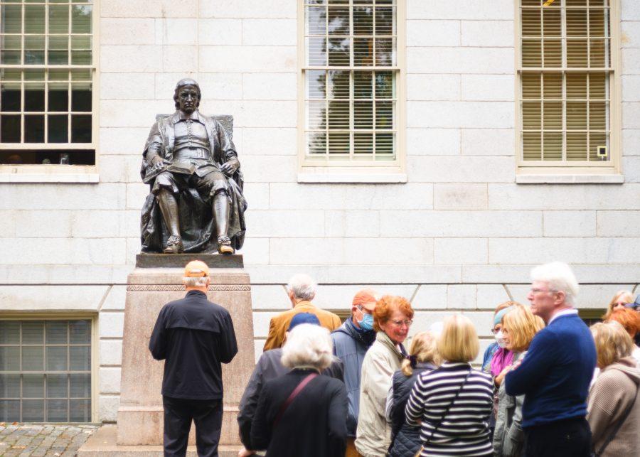 Tourists crowd around John Harvard’s statue on the Harvard University campus in Cambridge.