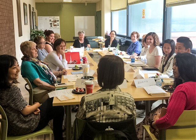 OLLI members talk and laugh around a table.