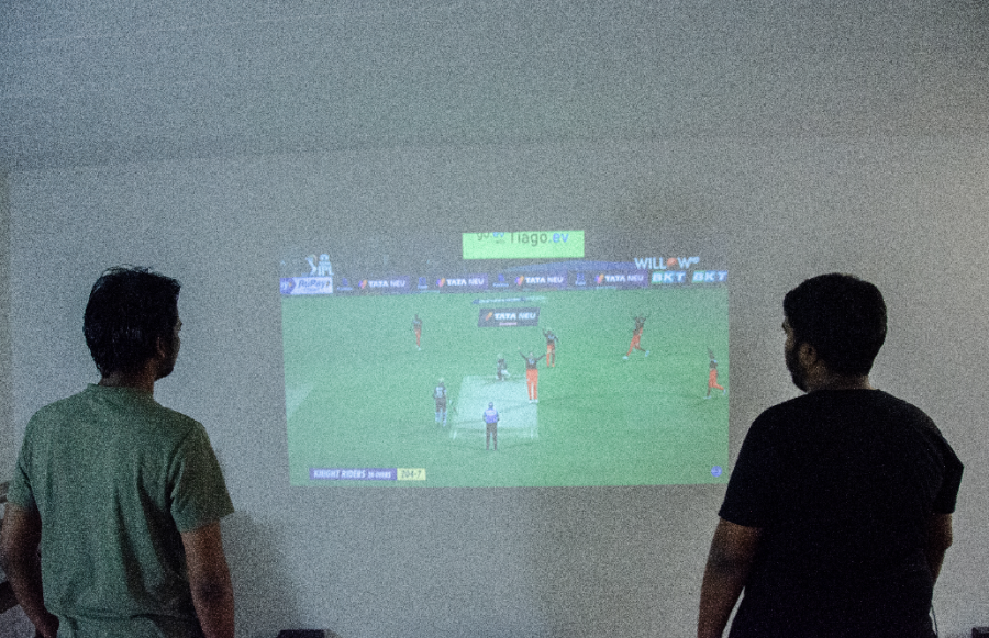 Two roommates watch cricket together in their living room. Photo by Saichand Chowdary (He/Him) / Mass Media Staff.