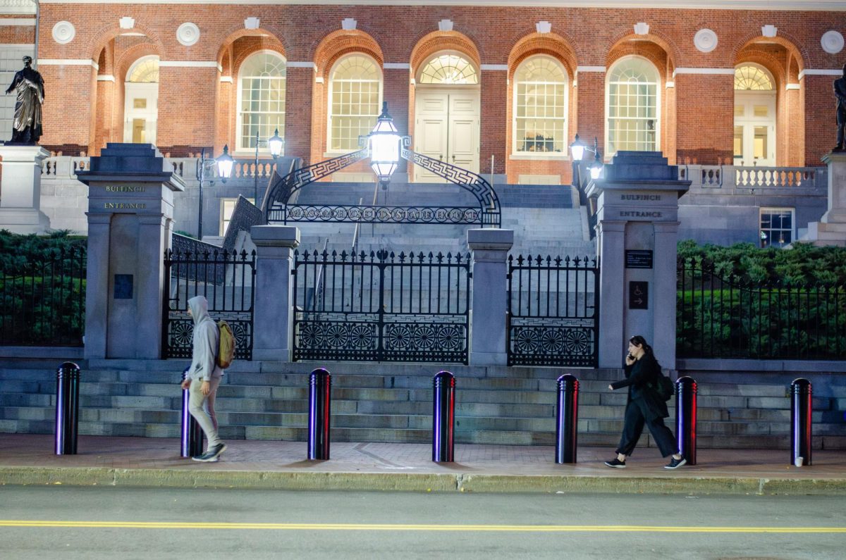 Two pedestrians pass by the Massachusetts State House. Photo by Saichand Chowdary / Mass Media Staff.