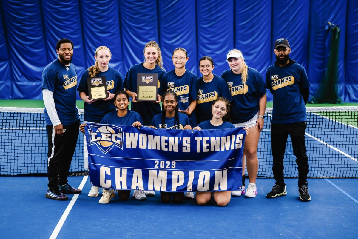UMass Boston Women’s Tennis team poses for a photo after their LEC championship win. Photo by Salt Lake Photo Company / Beacons Athletics.