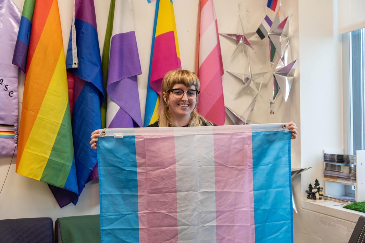 A member of the Queer Student Center holds up a transgender pride flag. Photo by Dong Woo Im / Mass Media Staff.