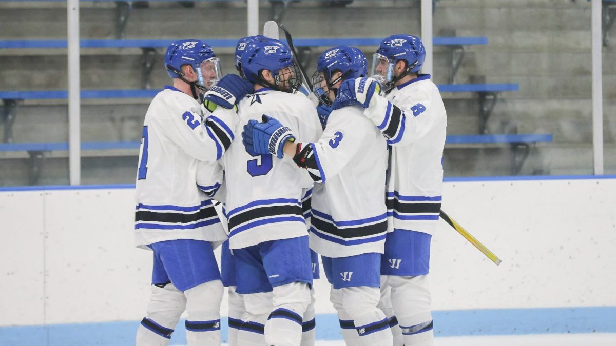 Men’s hockey players huddle during a home game. Photo courtesy of Beacon Athletics.