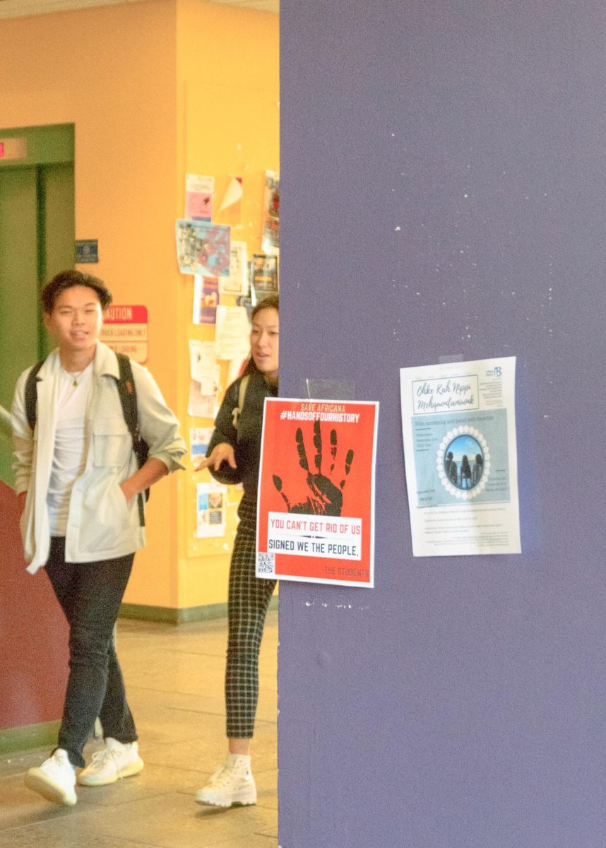 Students walk by a poster about the Africana Studies Department in the halls of the McCormack Building. Photo by Olivia Reid / Photography Editor.