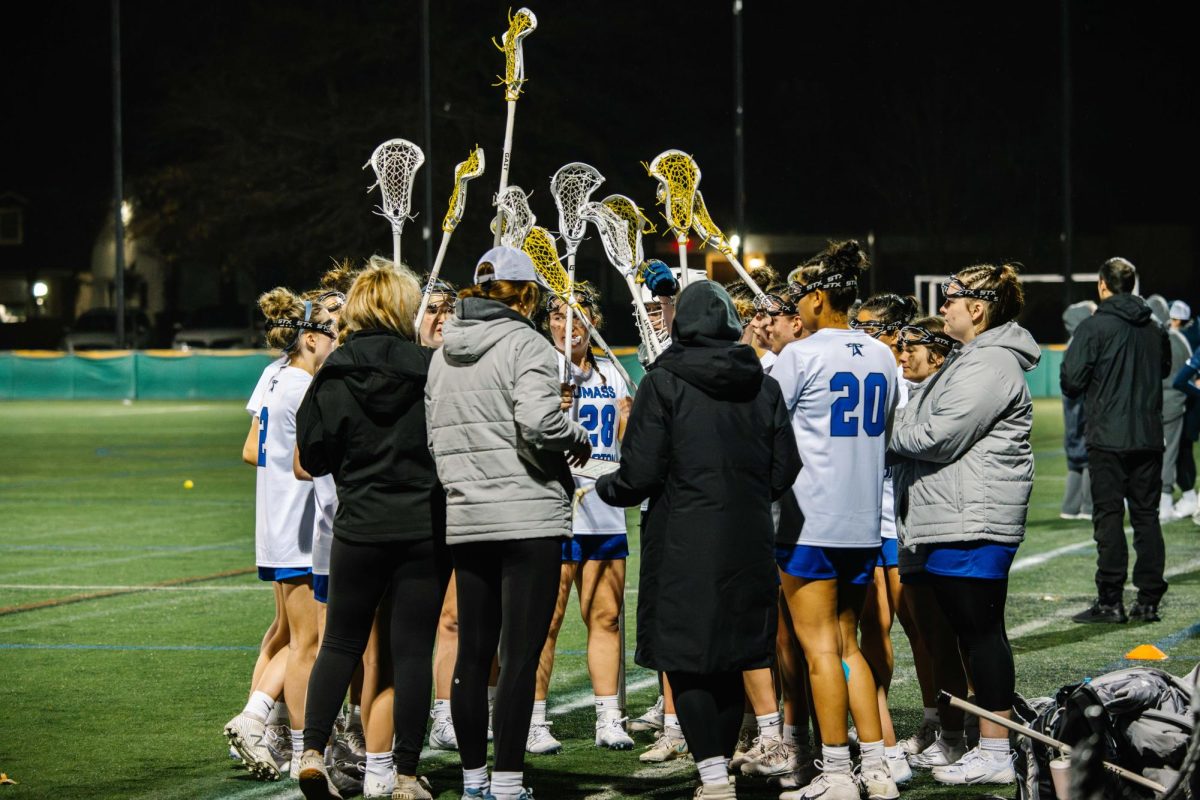 Women’s lacrosse huddles together at a home game. Photo by Dong Woo Im / Mass Media Staff.