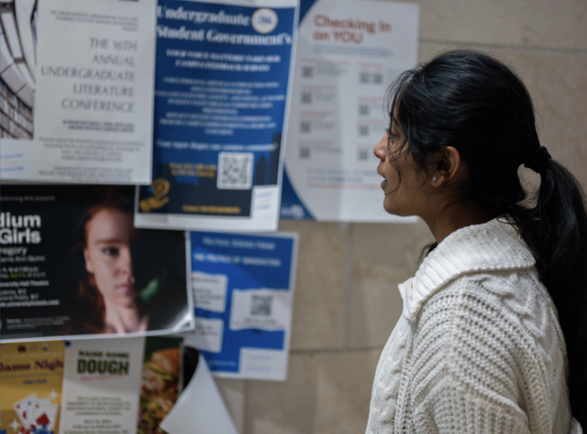 A student looks over posters hanging up in University Hall. Photo by Dong Woo Im / Mass Media Staff.