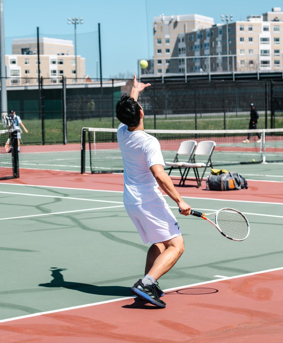A men’s tennis player prepares to serve during a home match. Photo by Olivia Reid / Photography Editor.