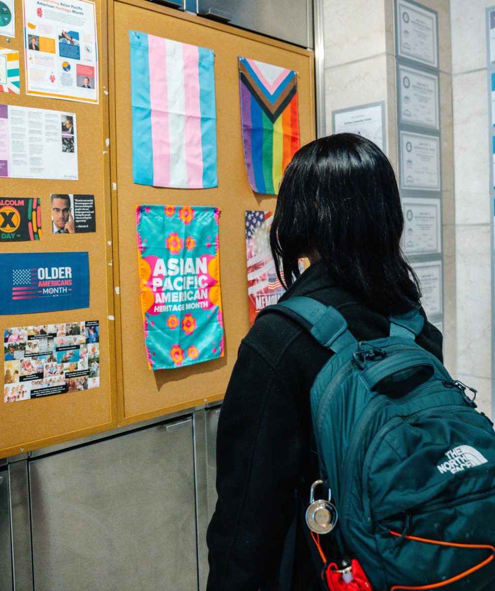 While walking around campus, a student looks at a poster highlighting AANHPI Heritage Month. Photo by Olivia Reid / Photography Editor