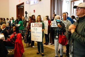 Protestors stood behind attendees at the campus information session.