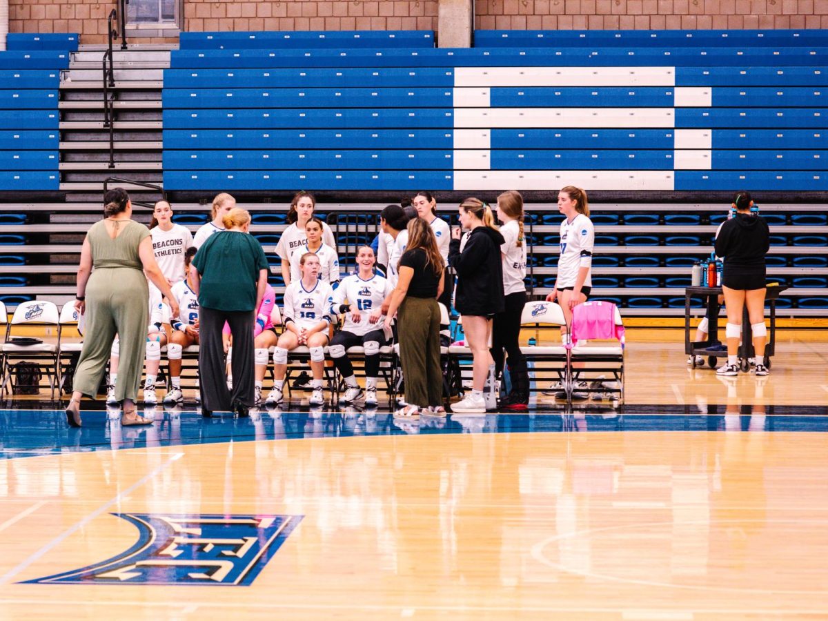 The team sits with coaches during a timeout. 