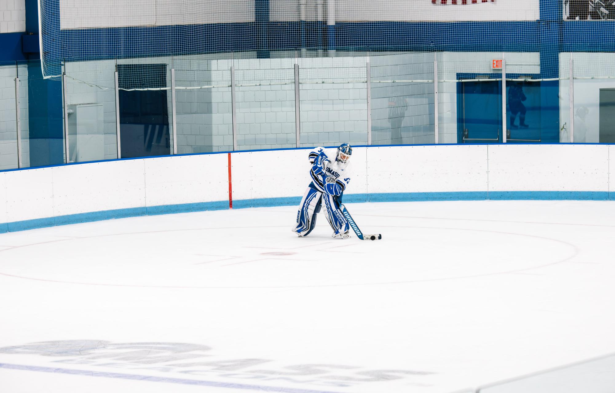 Men’s hockey player skates down the ice with the puck during their last game.