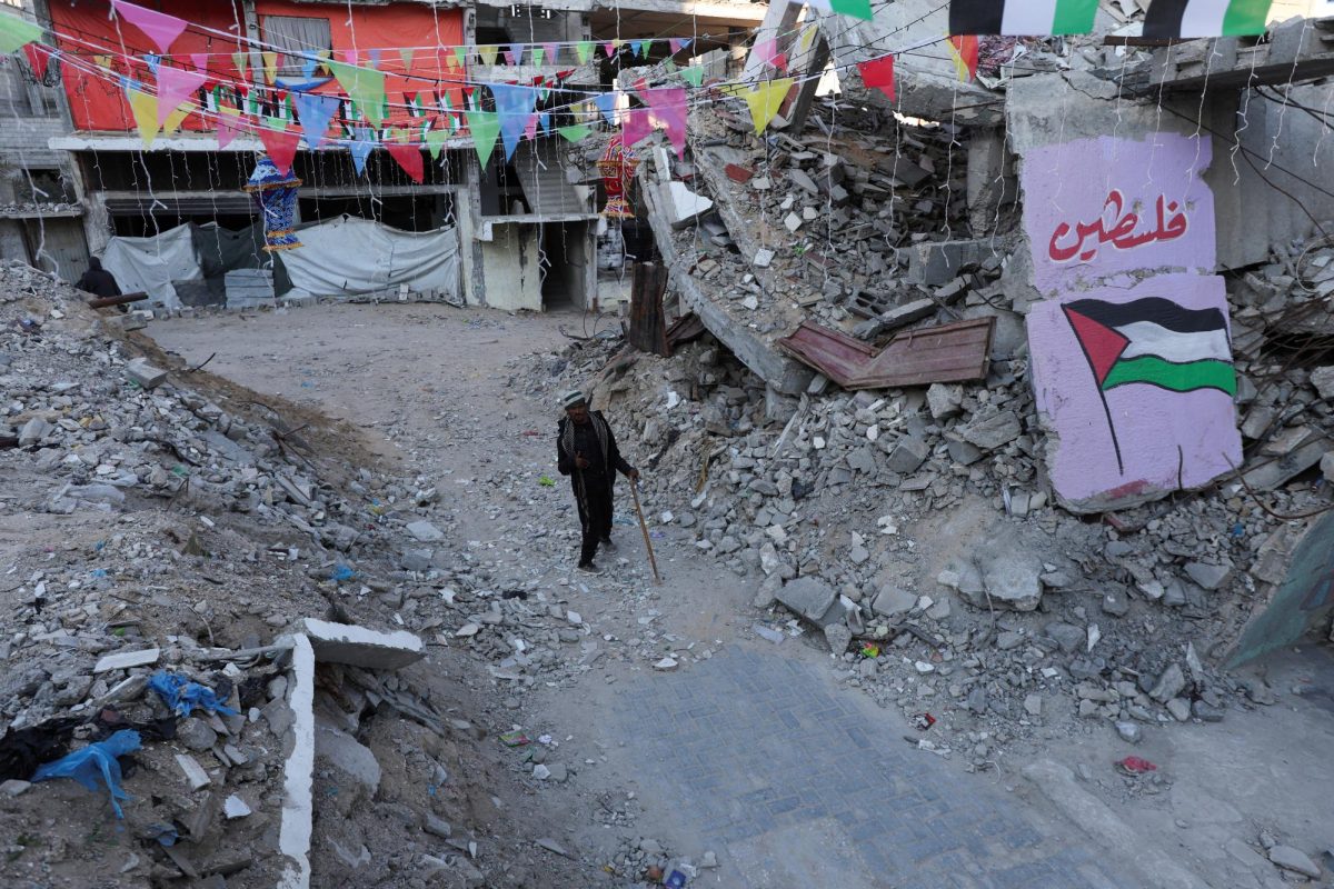 A Palestinian walks past graffiti and the rubble of buildings, ahead of the holy fasting month of Ramadan, amid a ceasefire between Israel and Hamas, in Khan Younis, in the southern Gaza Strip, February 27, 2025. REUTERS/Ramadan Abed