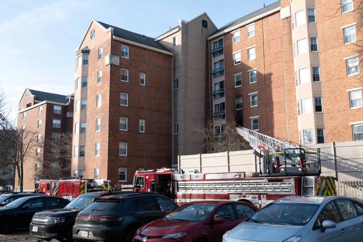 A Boston Fire Department ladder truck extends toward a burned window at 7:58 a.m. Tuesday.