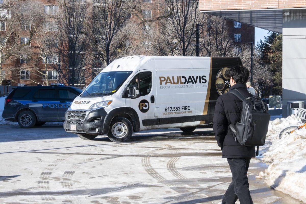 A van from Paul Davis Restoration, a flood remediation contractor, parks alongside a UMass Boston Police Department patrol car outside the East Residence Hall. 