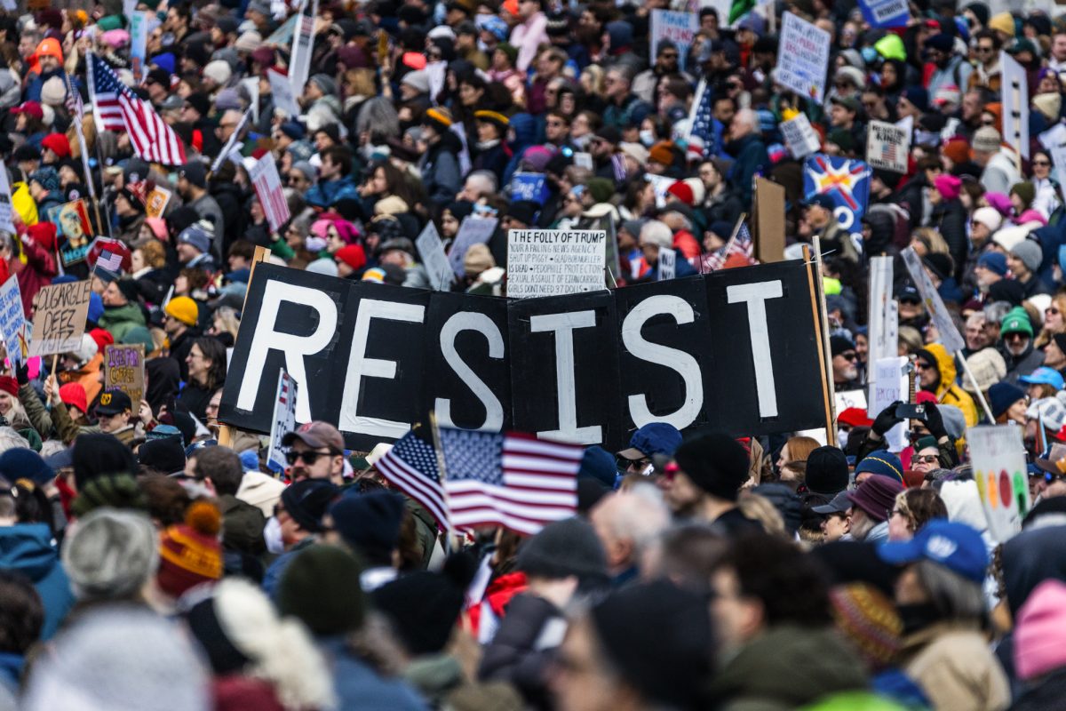 Rally attendees raise signs in solidarity. Thousands gathered to protest the Trump administration Saturday. Photo by Adam Strobel courtesy of The Daily Free Press